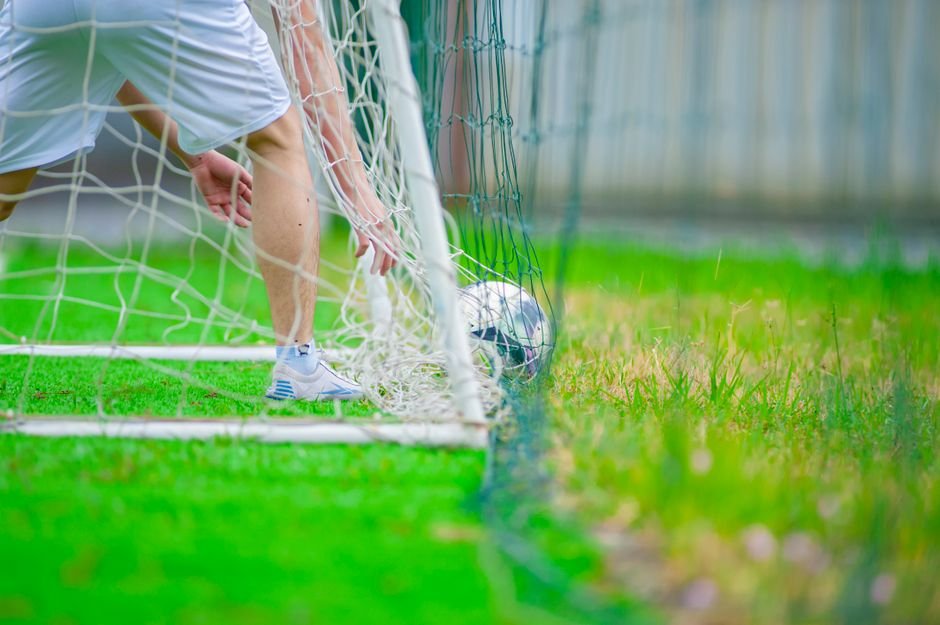 베트남 하노이에서 촬영한 푸른 잔디밭 위에서 축구 선수가 골대에서 공을 회수하는 모습입니다.